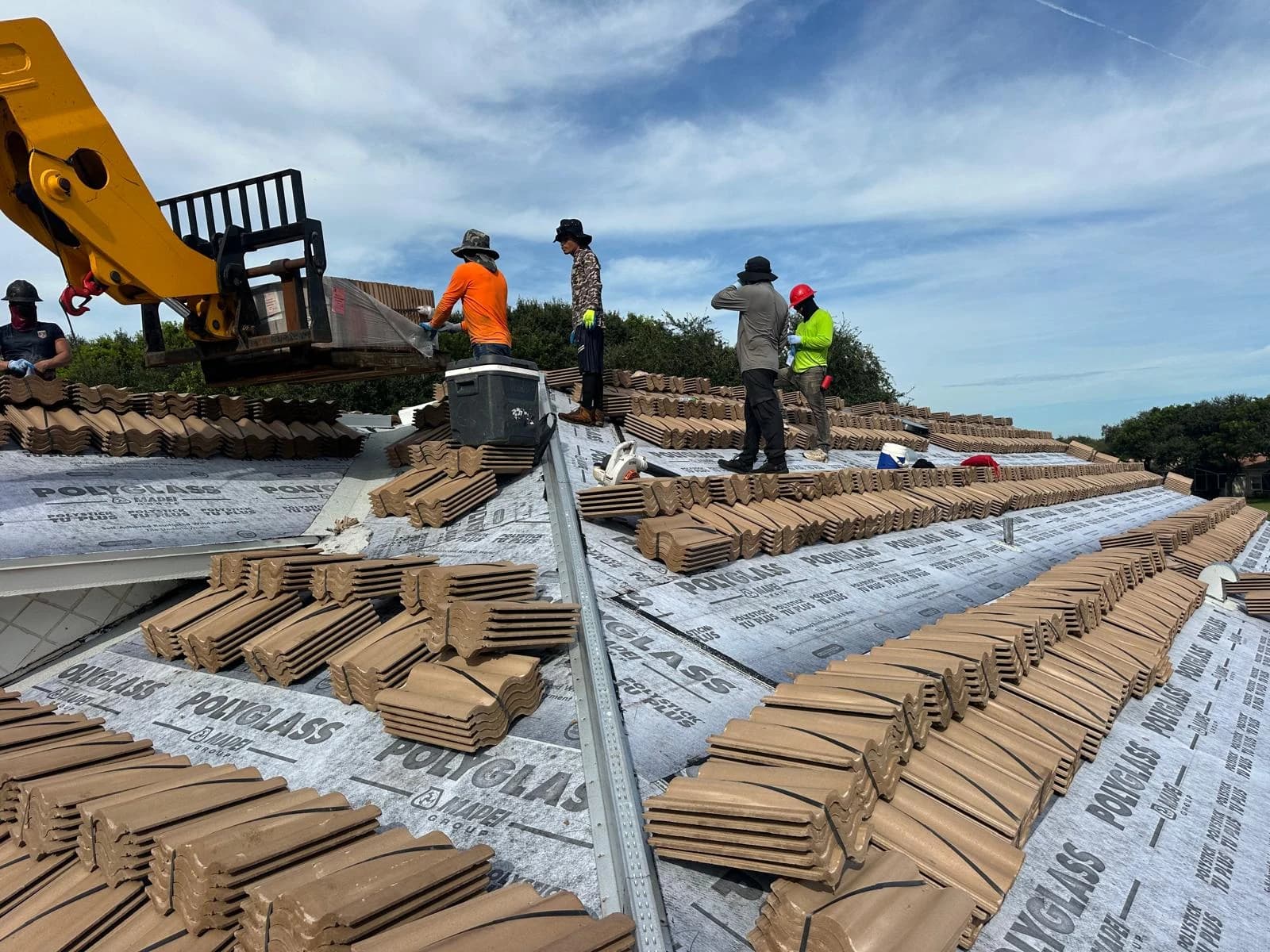 Telehandler lifting Estate roof tile to a rooftop crew during a Delray Beach-area loading project